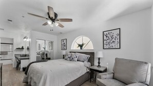 A modern bedroom with a bed, a desk, a chair, a ceiling fan, and artwork on the walls. - 5 minutes from strip|Pool|King|Stainless|300Mbps|4K|WD|BBQ (Branson)
