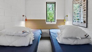 Una habitación con dos camas, una ventana que da a zonas verdes, un cartel de peces colgado en la pared y una lámpara colgante.