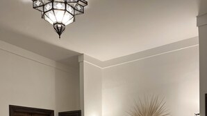 A bedroom with a large bed, two wall-mounted lights, a decorative mirror, and a wooden door. - Riad Laksiba  (Marrakech)