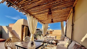 An outdoor patio with a covered seating area, a table, and chairs. - Riad Laksiba  (Marrakech)
