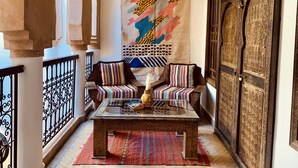 A traditional Moroccan interior with a sofa set, a coffee table, and a large tapestry. - Riad Laksiba  (Marrakech)