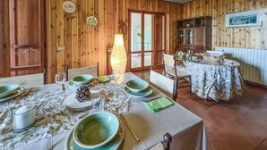 Un comedor con paredes de madera, una mesa dispuesta para cuatro personas con platos verdes y un aparador con vajilla.