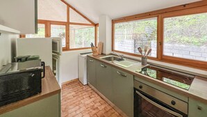 Cocina compacta con un lavamanos, un refrigerador pequeño y una ventana que proporciona luz natural.