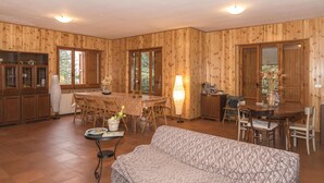 Un interior de madera con comedor, sofá y una mesa con un jarrón.