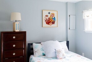 Un dormitorio con una cama, un aparador, una lámpara y un cuadro en la pared.