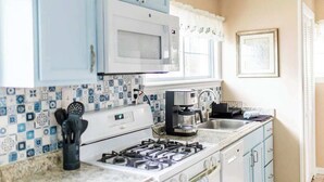 A kitchen with a gas stove, a microwave, and a coffee maker.