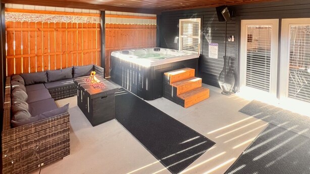 A modern interior with a wooden ceiling, a hot tub, a sofa, and a staircase leading to a door. - Creekside cottage with hot tub and fishing  (Brazil)