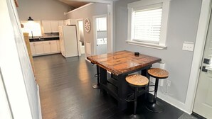A modern kitchen with dark wooden flooring, a central island with stools, and a bright ceiling light. - Creekside cottage with hot tub and fishing  (Brazil)