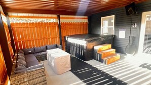 A spacious room with a wooden ceiling, a black and white striped rug, a sofa, a small table, and a bench. - Creekside cottage with hot tub and fishing  (Brazil)