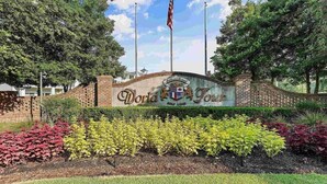 Un ingresso in mattoni con un cartello che riporta "World Tour Golf Links" e una bandiera americana.