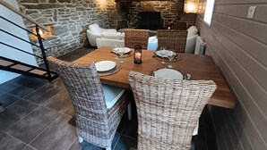 Ein Essbereich mit Steinsandsteinwand, Korbstühlen, einem Holztisch für zwei Personen und einem Fernseher im Hintergrund.