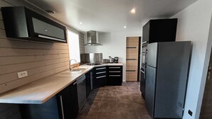 Eine moderne Küche mit dunklen Schränken, einem Edelstahlkühlschrank und einem Gasherd.