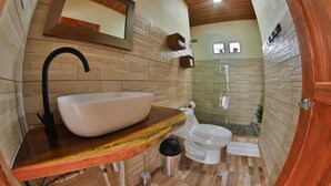 Une salle de bain comprenant un grand lavabo sur pied, des toilettes et un espace douche.