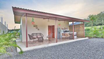 Una casa con porche cubierto, mobiliario exterior y espacio para la cocina.