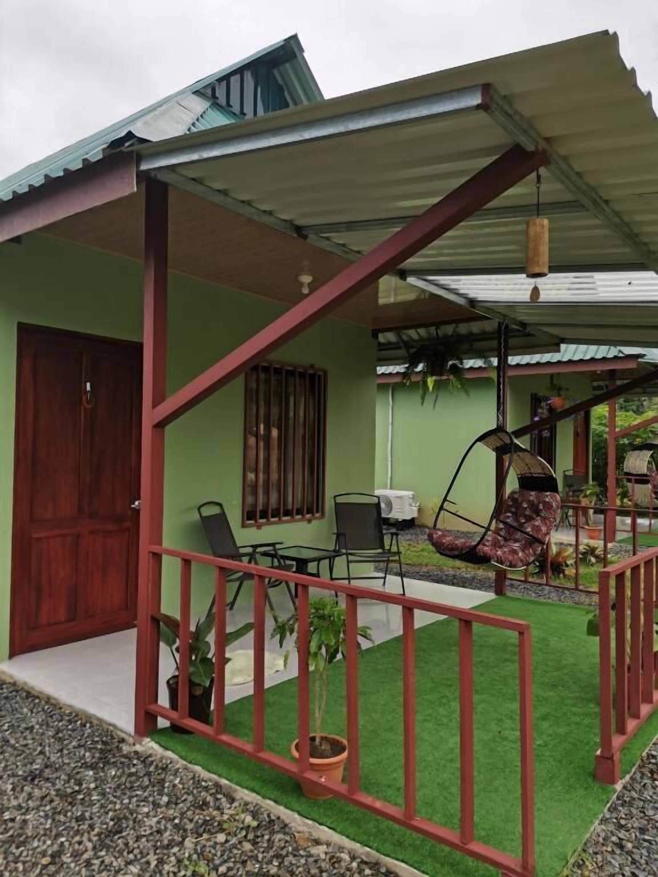 A house with a porch, a swing chair, a table, and potted plants.