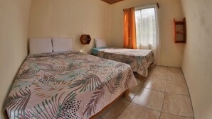 Une chambre avec deux lits, un plafond en bois, une fenêtre avec des rideaux et une étagère fixée au mur.