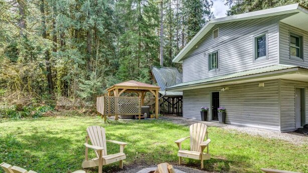 A wooden house with a fire pit and Adirondack chairs in the yard.