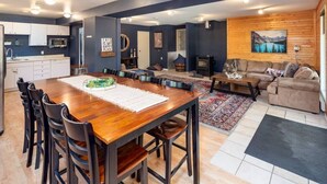 A modern living space with a wooden dining table, kitchen area, and a cozy seating area with a fireplace.