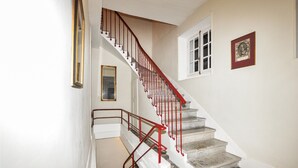 A staircase with red railings and a patterned rug at the bottom.
