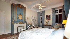 A bedroom with a bed, a ceiling fan, a mirror, and a window with curtains.