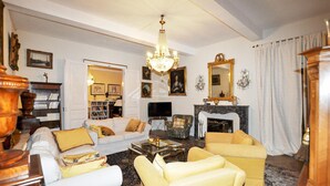 A living room with a white sofa, yellow armchairs, a chandelier, a fireplace, and a television.
