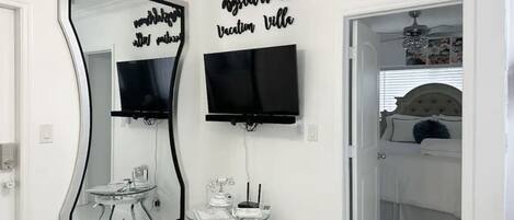 Une chambre à coucher avec un lit, une télévision, un miroir et un panneau décoratif au mur.