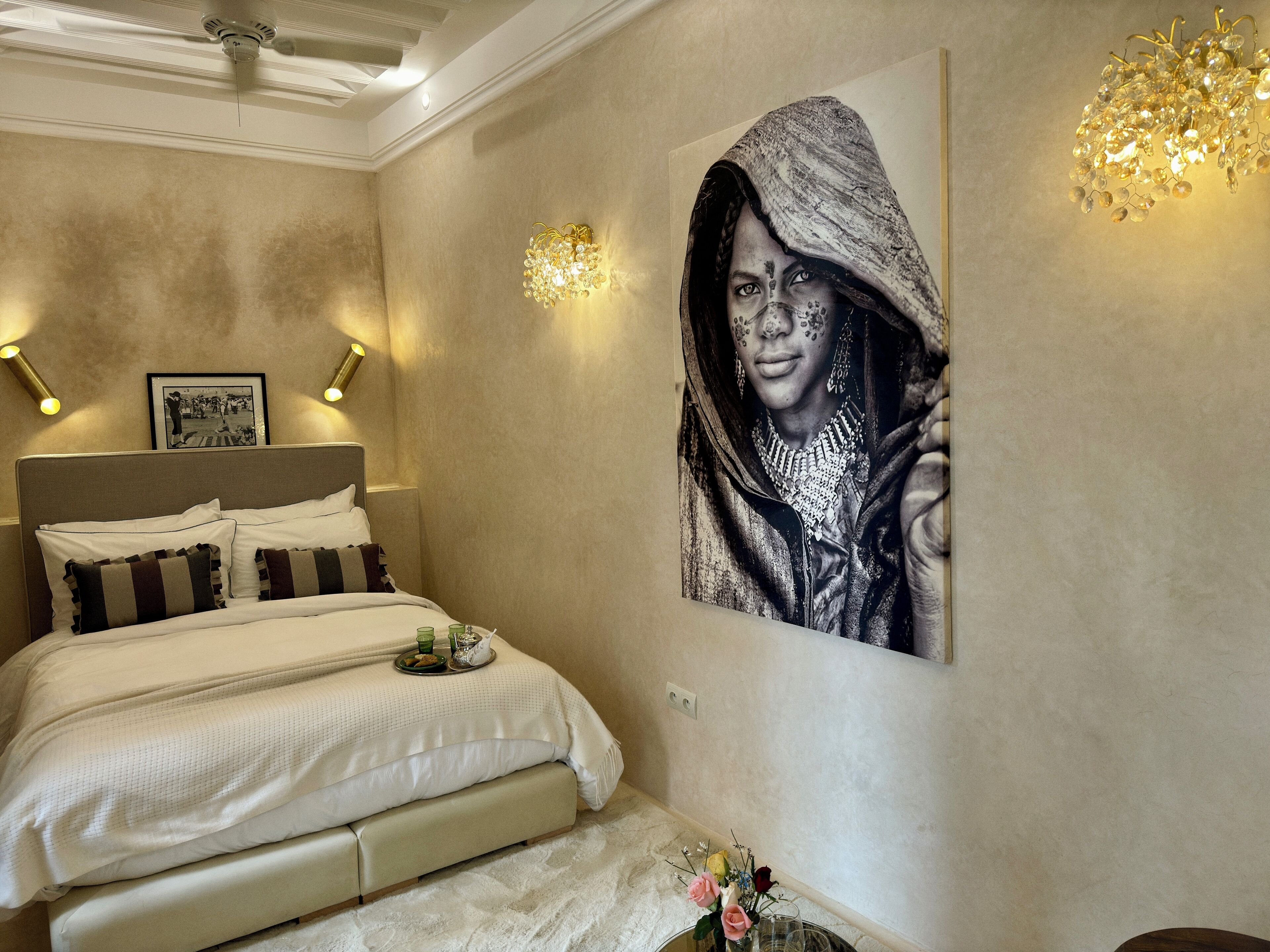 Une chambre à coucher avec un lit, un tableau accroché au mur et un lustre.
