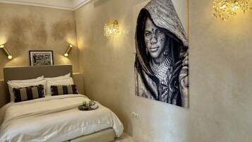 Une chambre à coucher avec un lit, un tableau accroché au mur et un lustre.