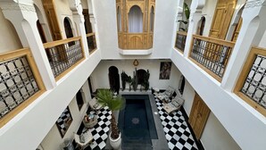 A courtyard with a checkered floor, a central pool, and a wooden structure with a tiled roof. - Riad LallaBaya (Marrakech)