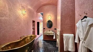 A bathroom with a freestanding bathtub, a sink with a mirror, and a towel rack.