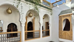 A multi-level interior with arched doorways, hanging lanterns, and a wooden balcony railing. - Riad LallaBaya (Marrakech)
