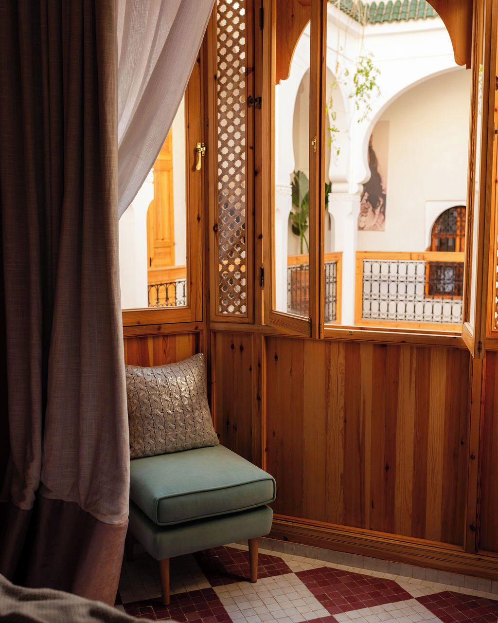 Una habitación con un banco de madera, una ventana con vista a un patio, y un biombo decorativo.