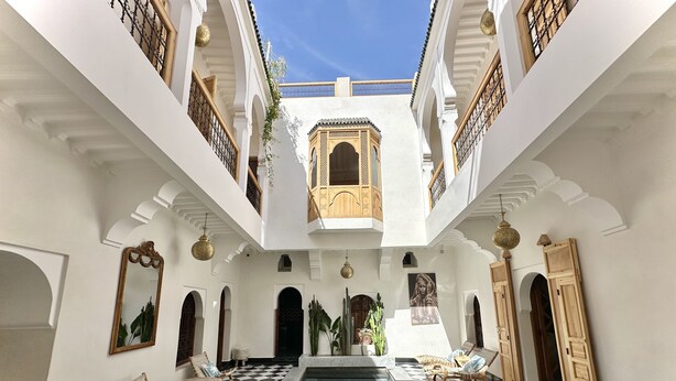 A courtyard with a checkered floor, a central pool, and a wooden door. - Riad LallaBaya (Marrakech)