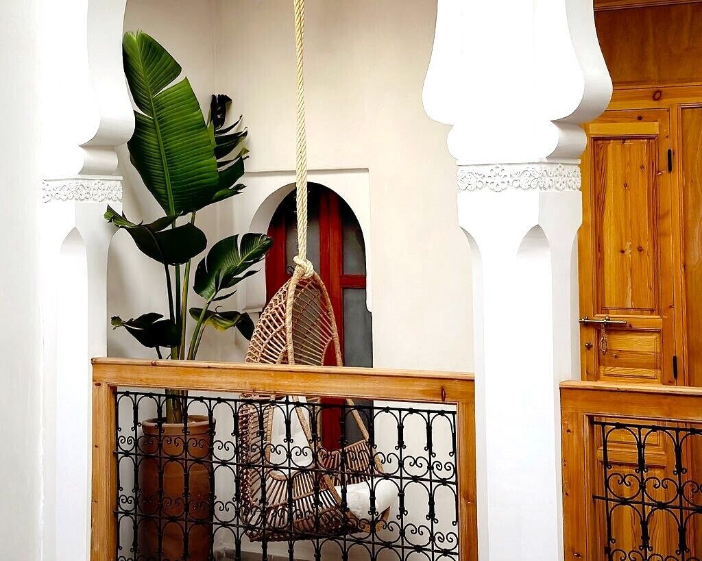 Een kamer met een hangstoel, een potplant en een houten kast.