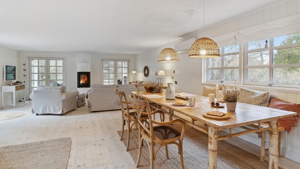 A spacious living room with a large wooden dining table, comfortable seating, and a fireplace.