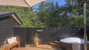 A wooden deck with a hot tub, a bench, and a potted plant.