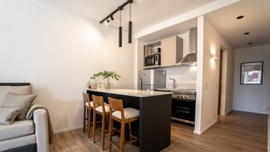 A modern kitchen with a central island, bar stools, a microwave, and a stove. - Barrancas Quality Apartments (Buenos Aires)