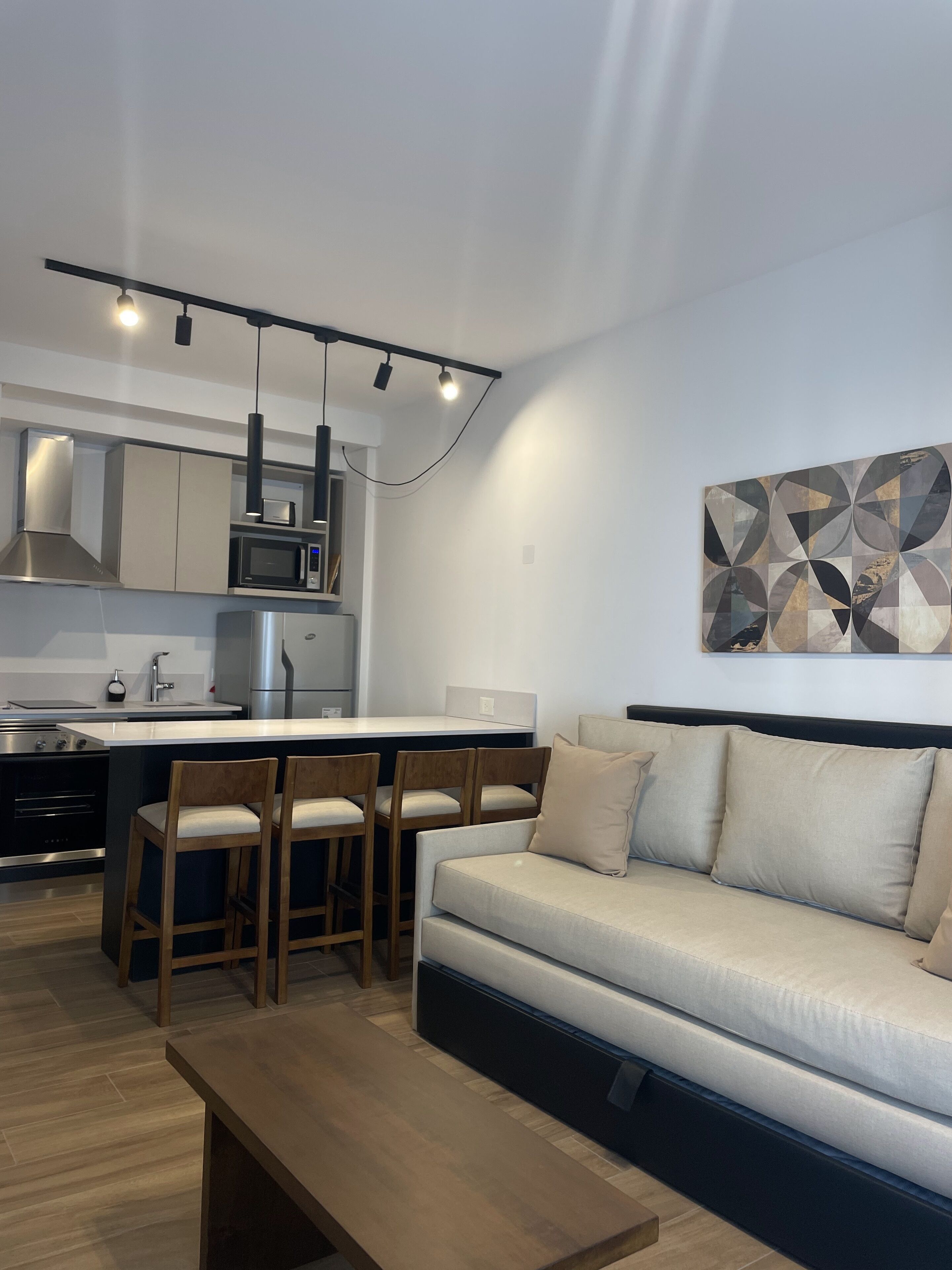 A modern kitchen with a central island, bar stools, a sofa, and a coffee table.