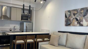 A modern kitchen with a central island, bar stools, a sofa, and a coffee table.