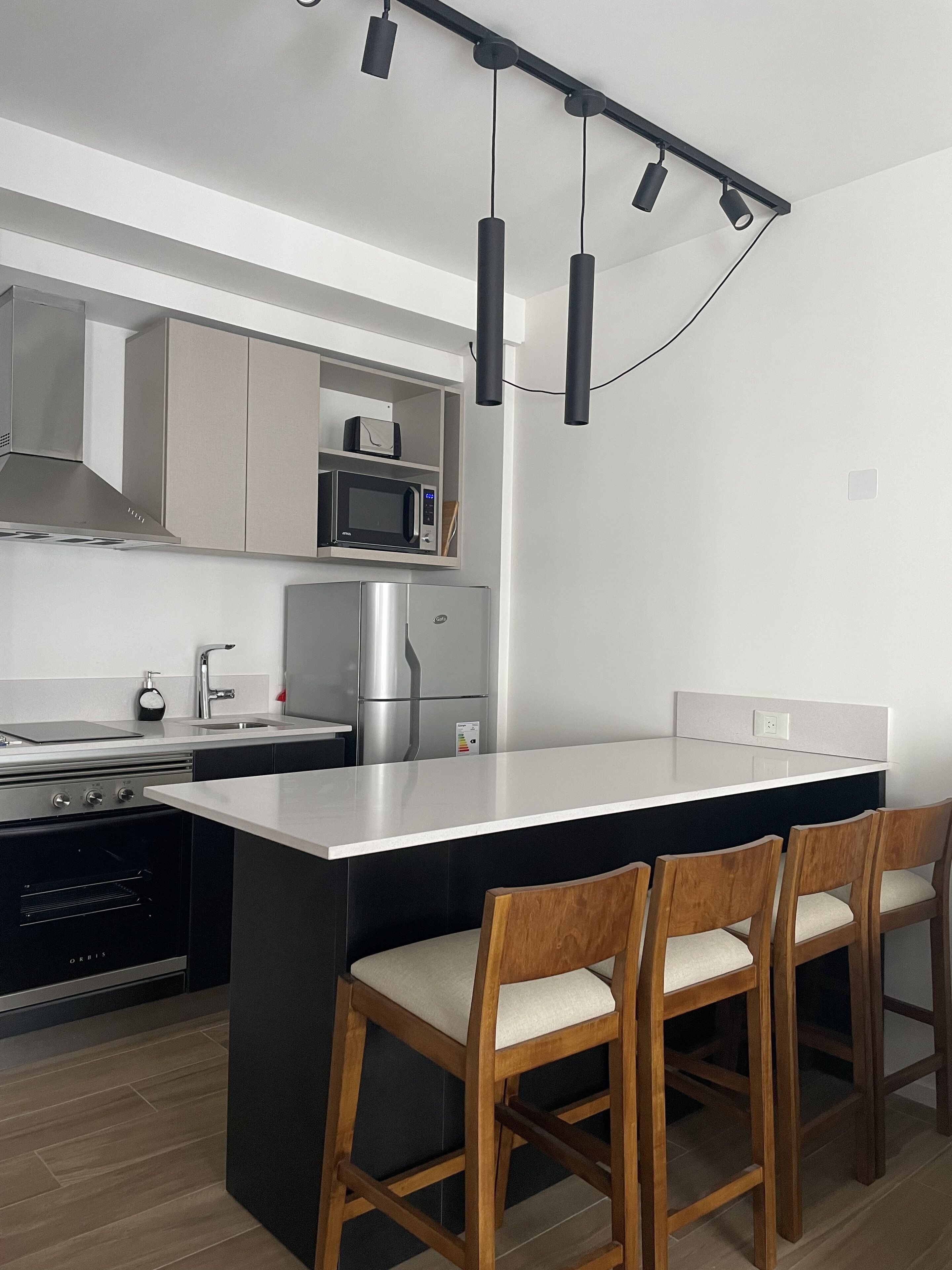Una cucina moderna con isola centrale, elettrodomestici in acciaio inossidabile e sgabelli da bar in legno.