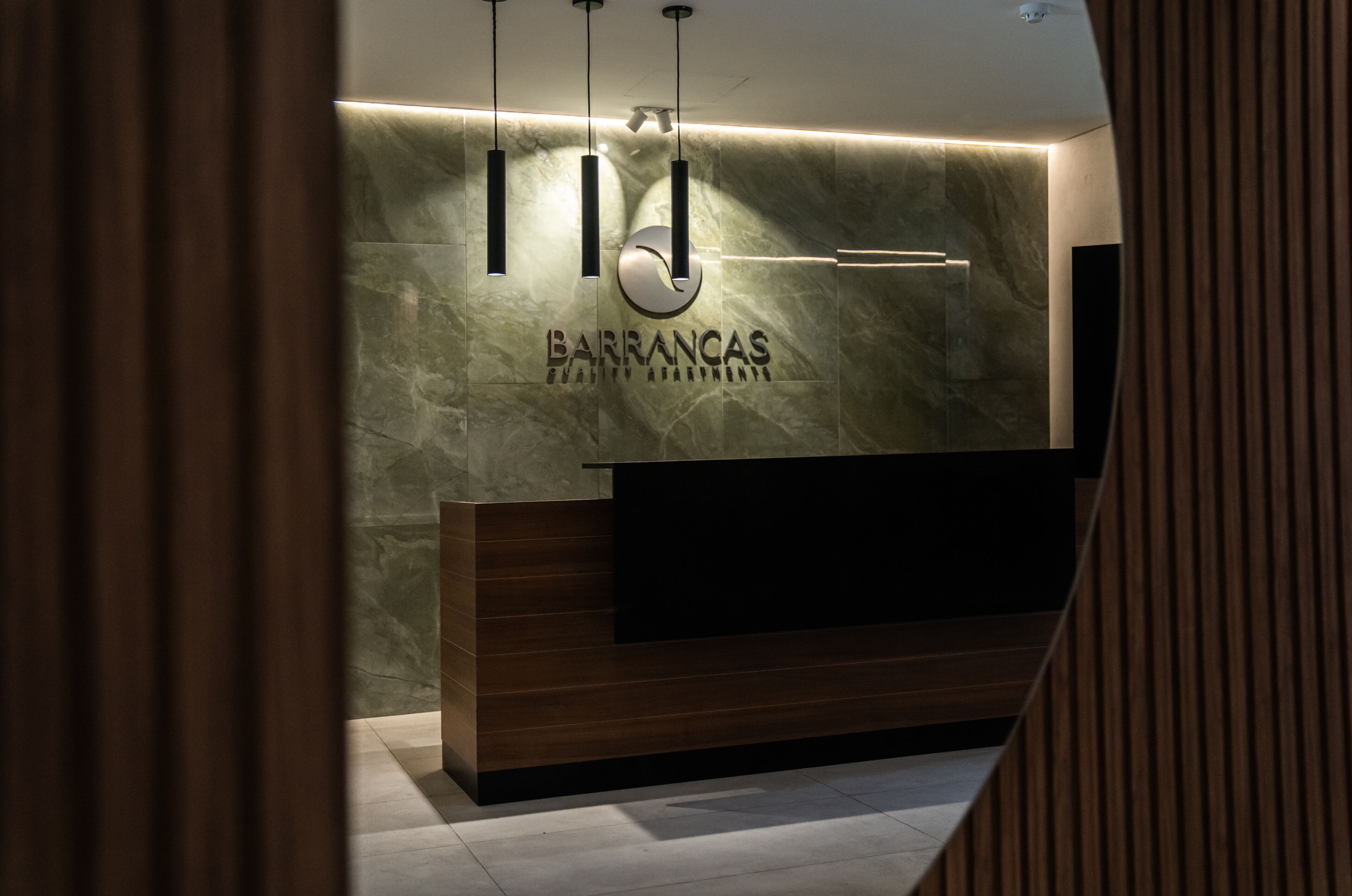 A reception desk with a marble wall and a logo.