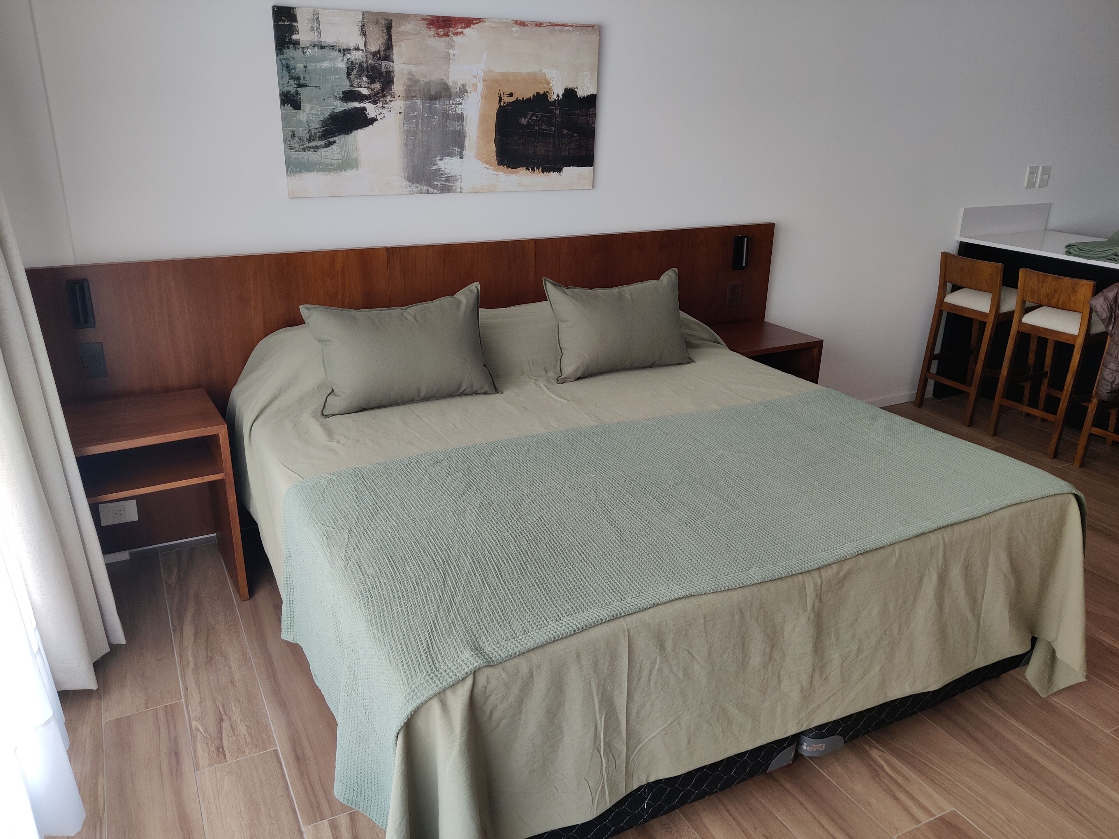 Un dormitorio ordenado con una cama, dos mesitas de noche, un escritorio y una silla.