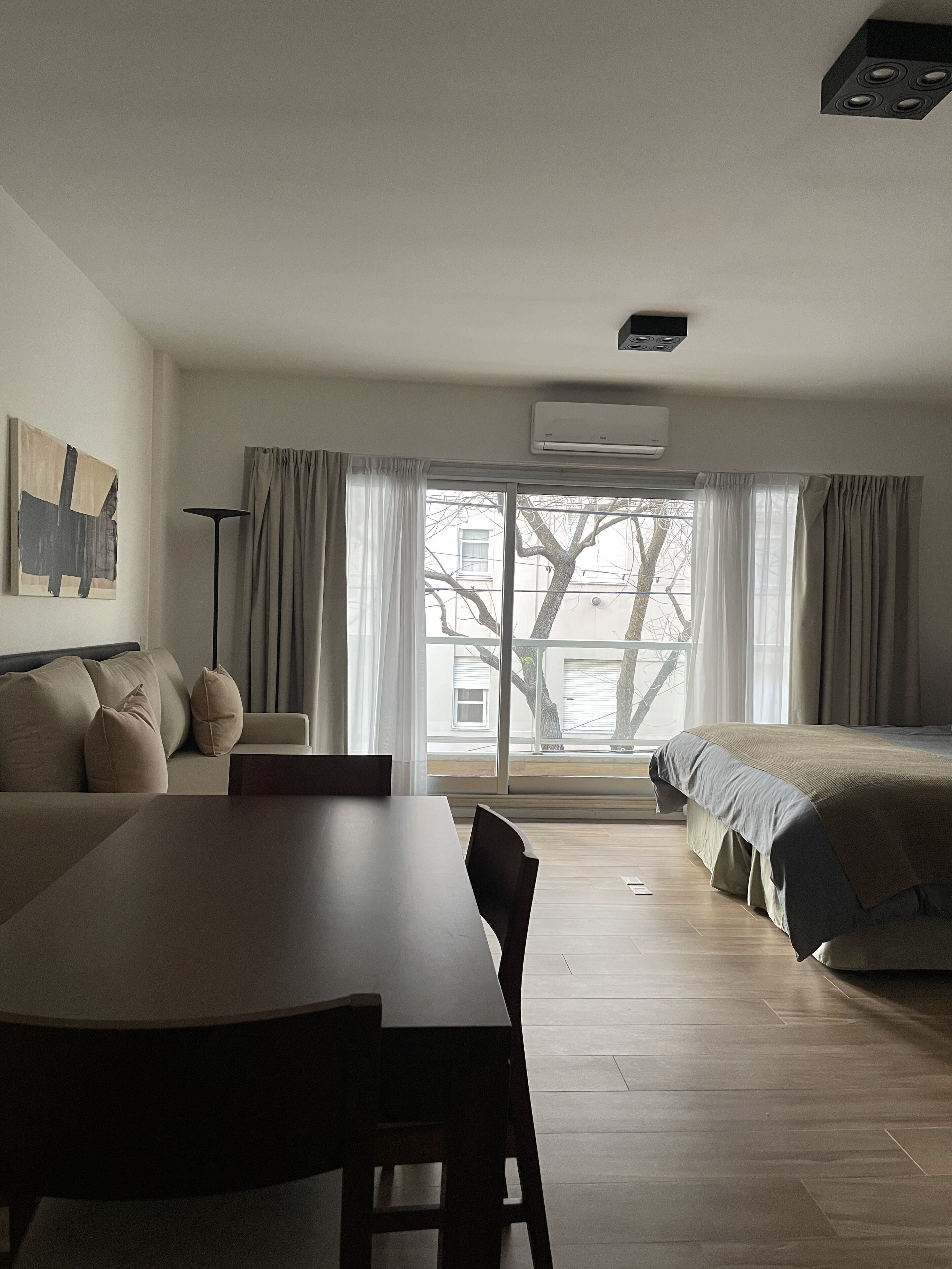 A modern, well-lit room with a dining table, a sofa, and a bed.