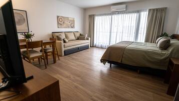 A hotel room with a bed, a sofa, a desk, and a television.