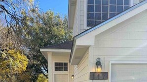 Une maison d’habitation avec un jardin devant, une clôture en bois et une porte de garage.