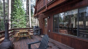 Eine Holzterrasse mit Grill, Tisch und Stuhl.