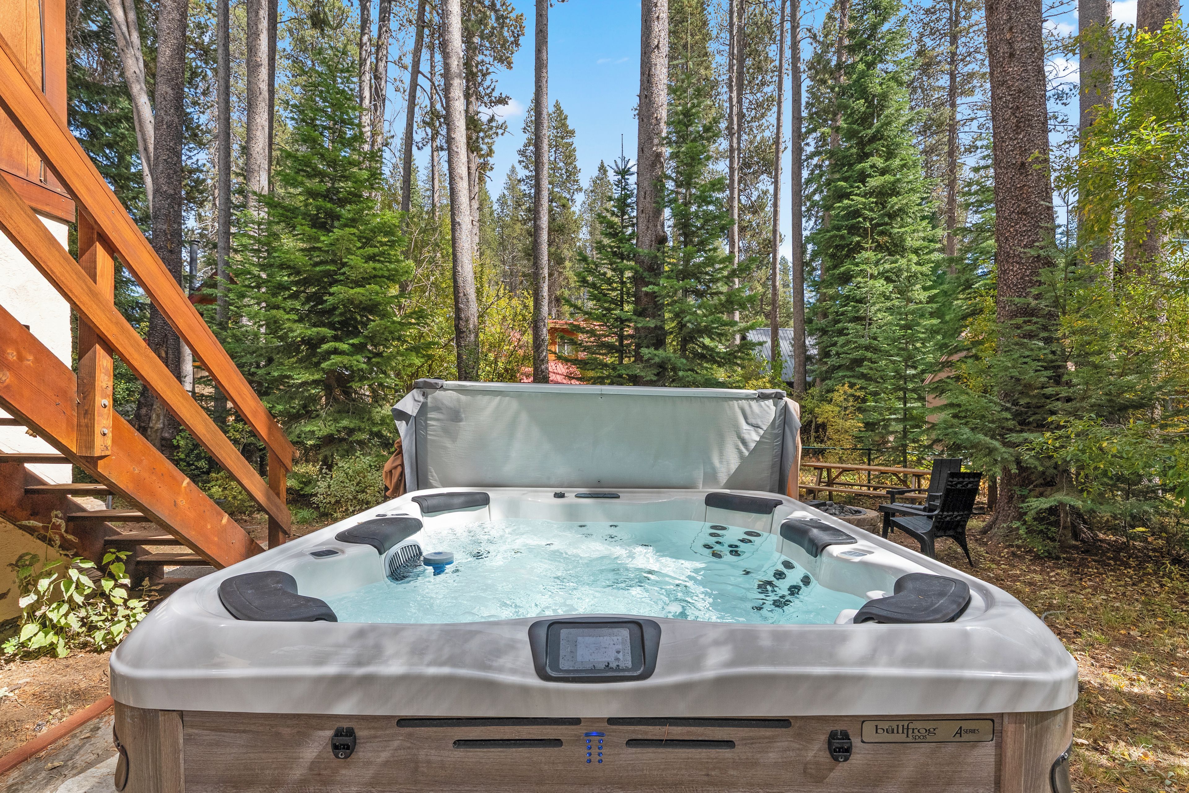 Ein Whirlpool in bewaldeter Landschaft mit Holzterrasse und Picknicktisch.