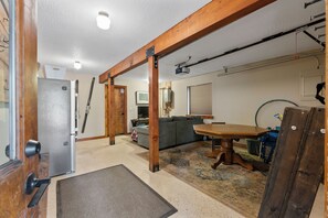 A spacious room with a wooden ceiling, a large table, a sofa, and a television.