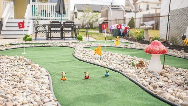 Un parcours de mini-golf avec une maison en arrière-plan.