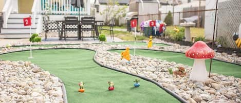 Un parcours de mini-golf avec une maison en arrière-plan.